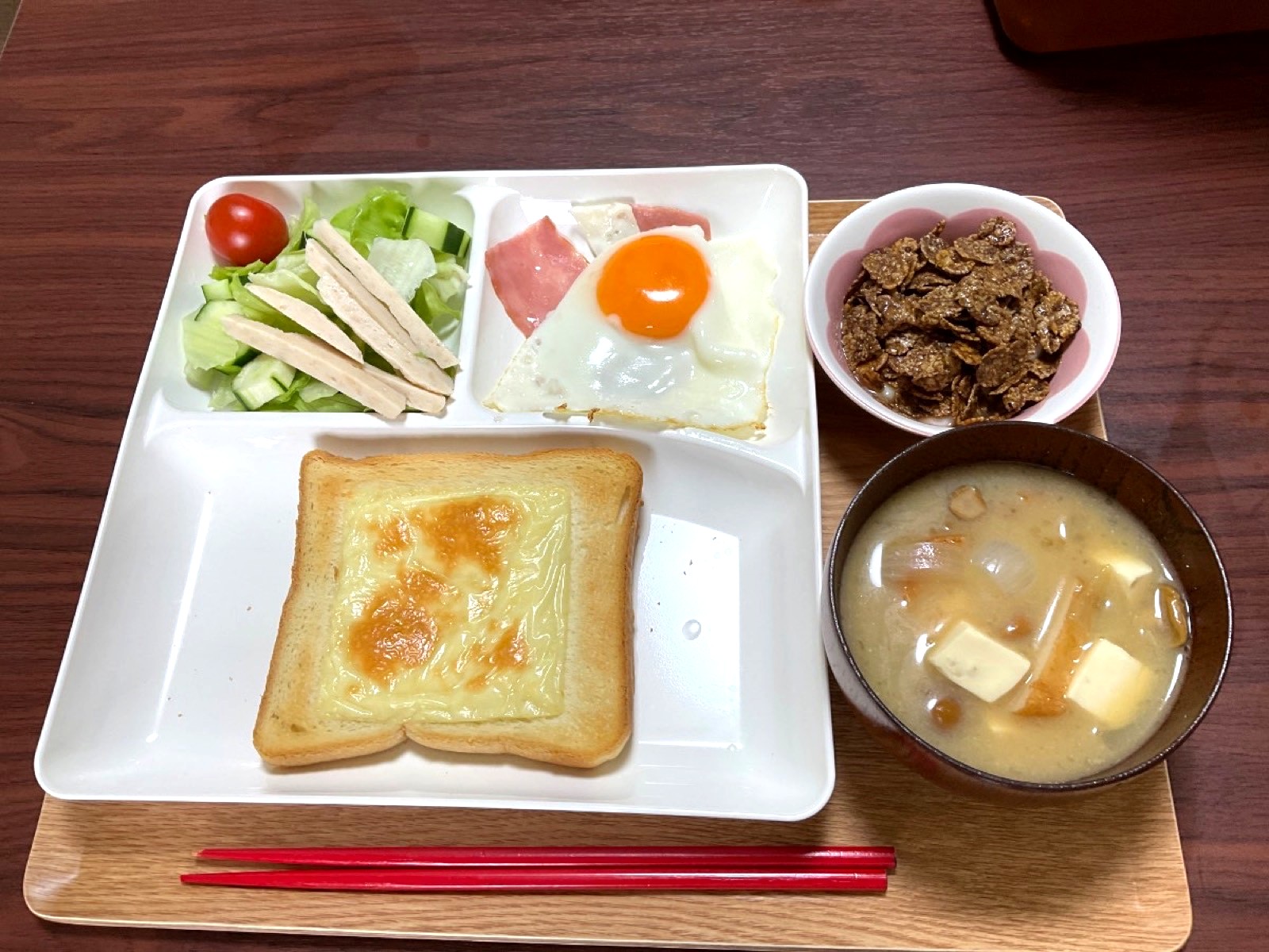 にこにこビレッジで提供している朝食の一例。チーズトースト、ハムエッグ、サラダ、コーンフレーク、豆腐の味噌汁